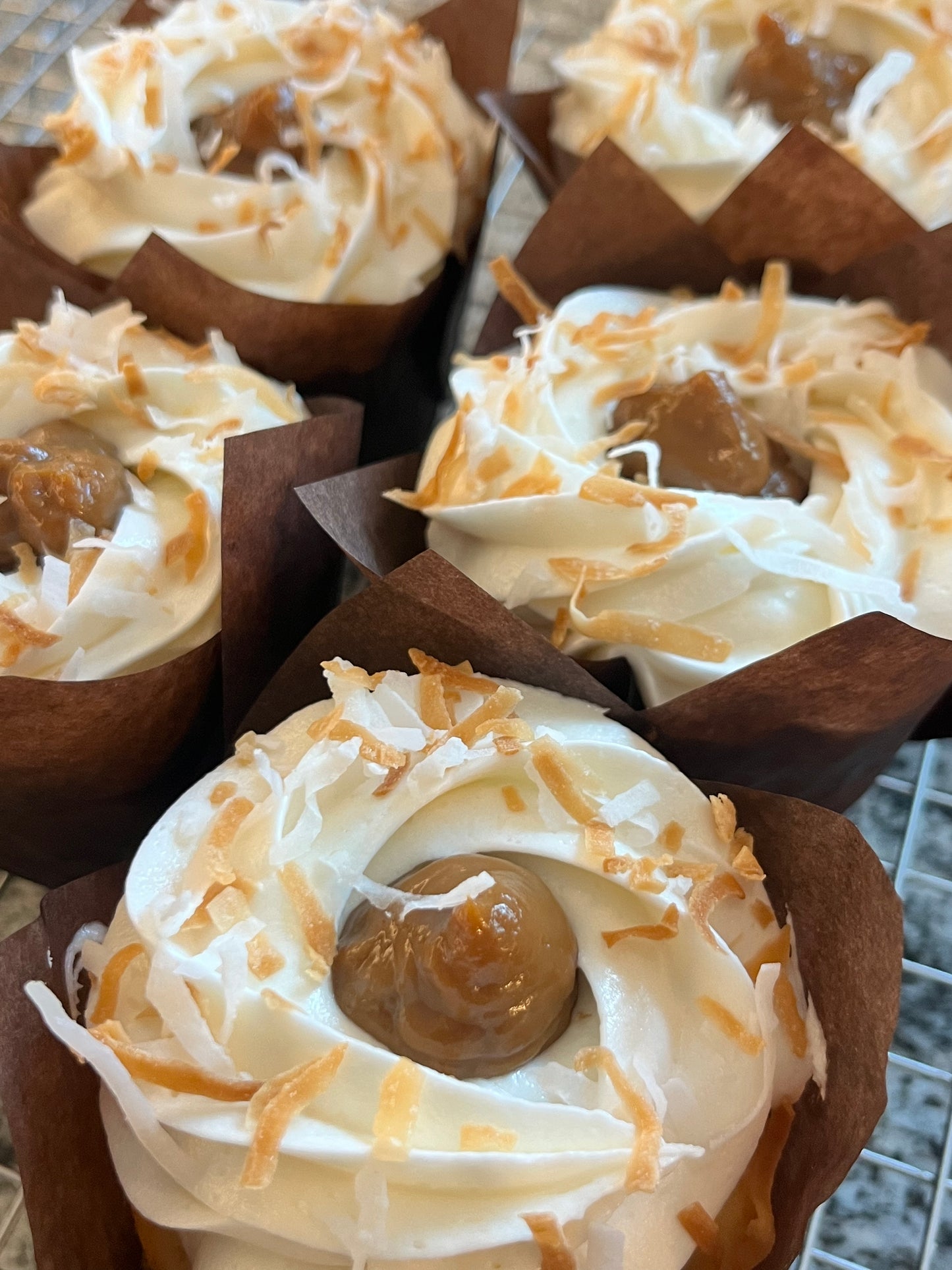 Coconut Dulce de leche cupcakes sit down on a bakers rack