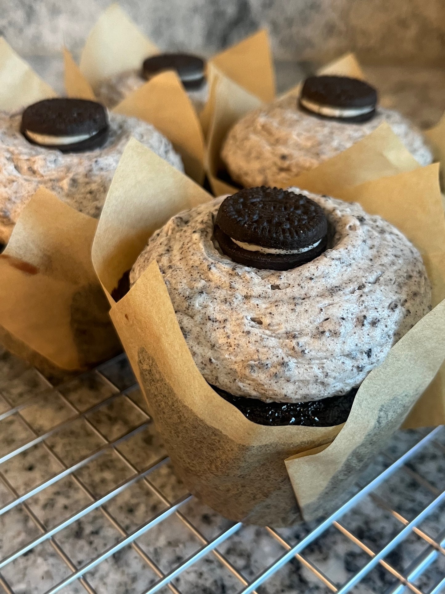 An image of four mouthwatering “O” So Good Cupcakes (chocolate cake with vanilla Oreo buttercream topped with a mini Oreo cookie).