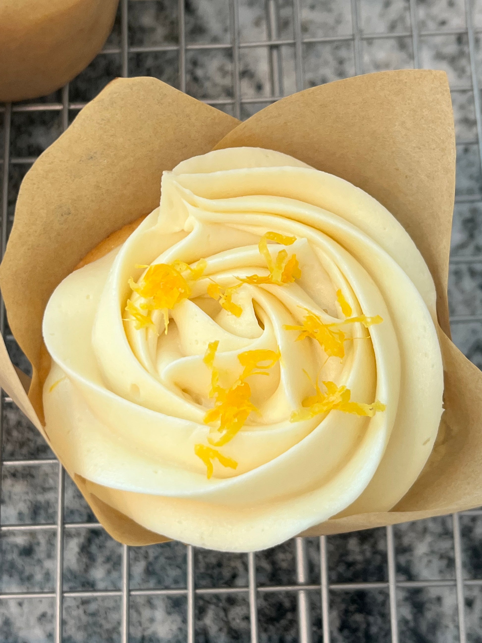 A single Pucker Up! Cupcake topped with fresh lemon zest.