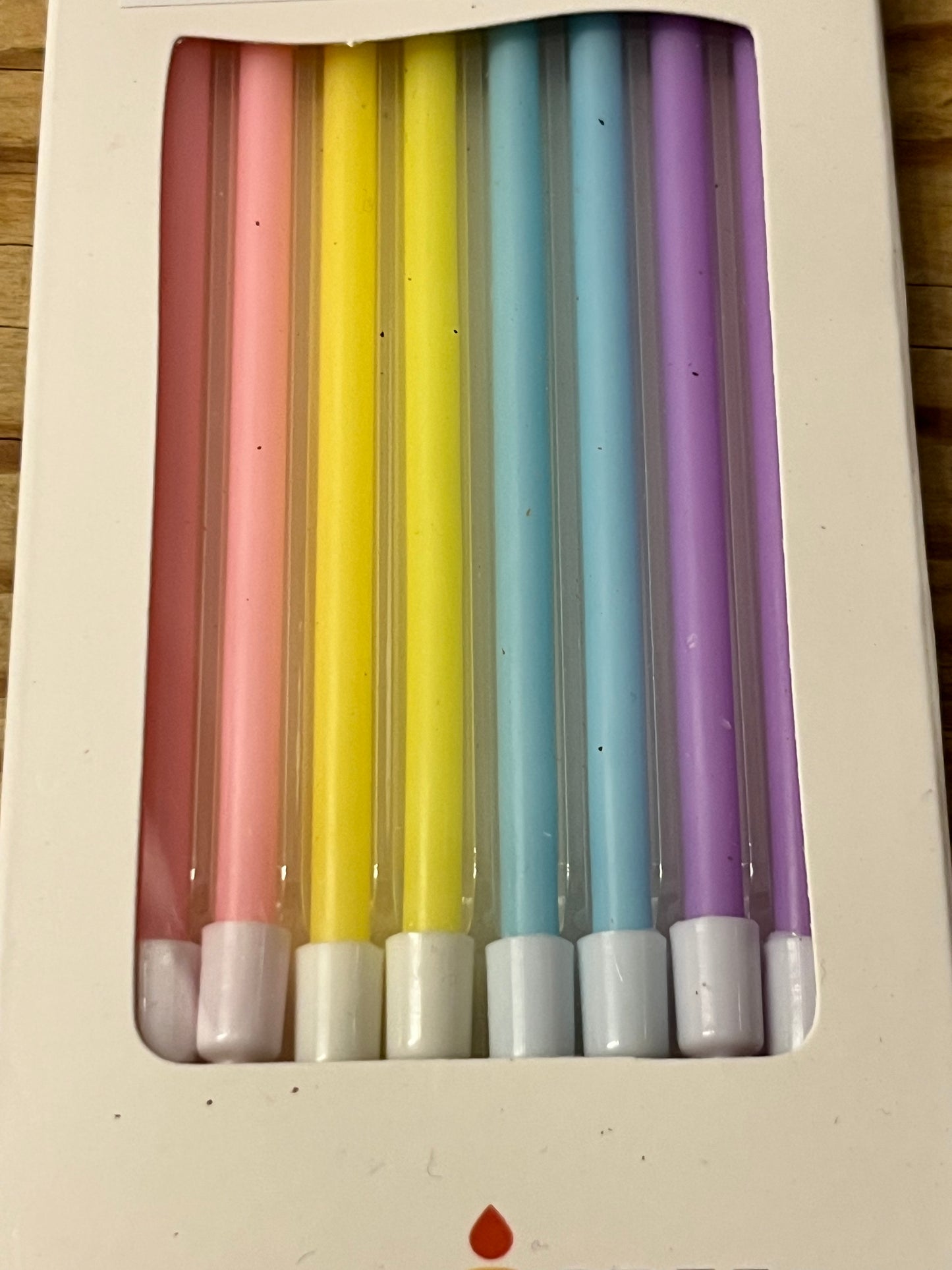 A closer look at a box of eight 4.7" tall skinny candles.  Each pack of eight candles contains two light pink candles, two yellow candles, two light blue candles and two light purple candles.   The candles are matte, not shiny, elegant and petite, yet tall and lovely.