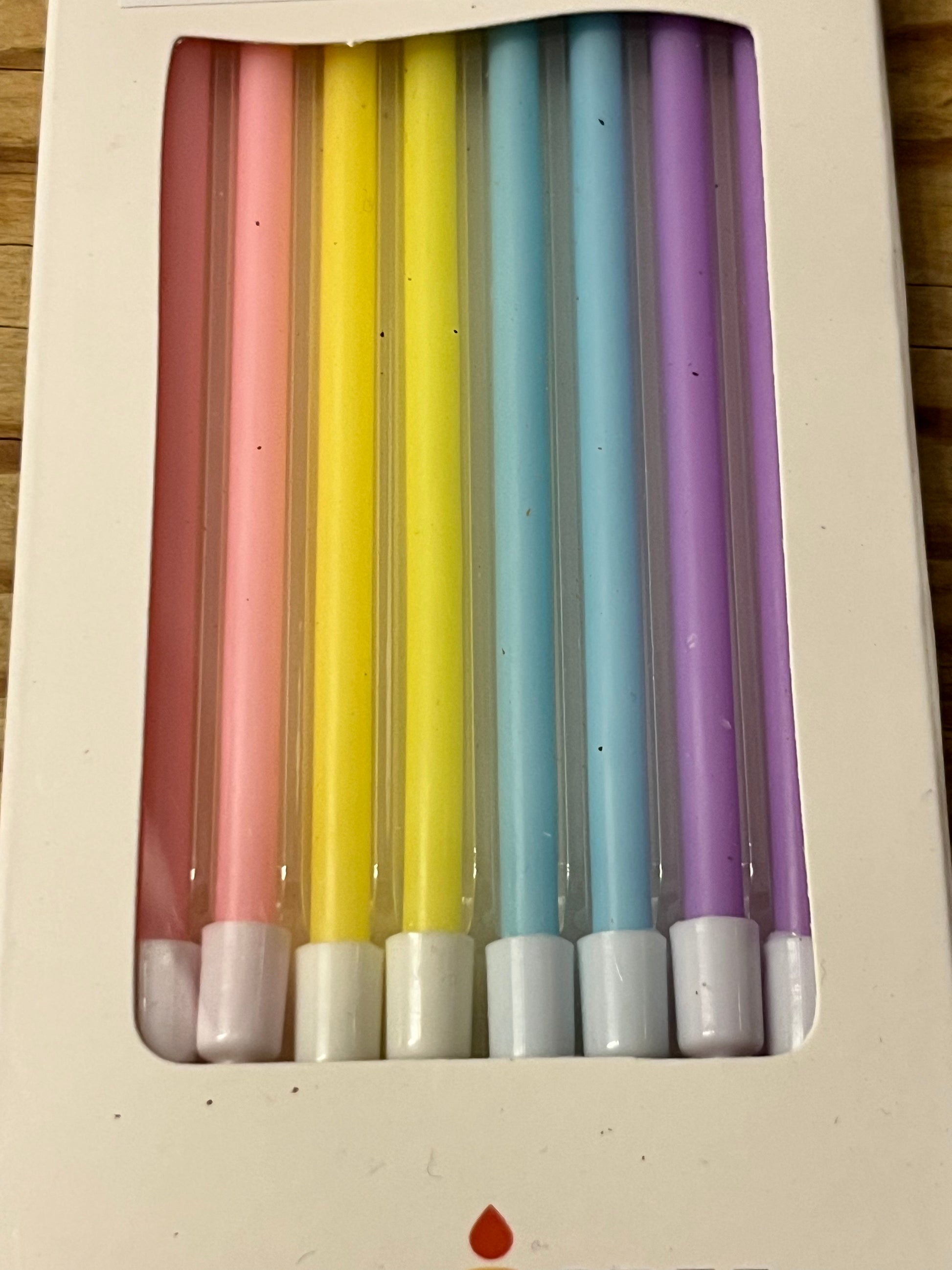 A closer look at a box of eight 4.7" tall skinny candles.  Each pack of eight candles contains two light pink candles, two yellow candles, two light blue candles and two light purple candles.   The candles are matte, not shiny, elegant and petite, yet tall and lovely.