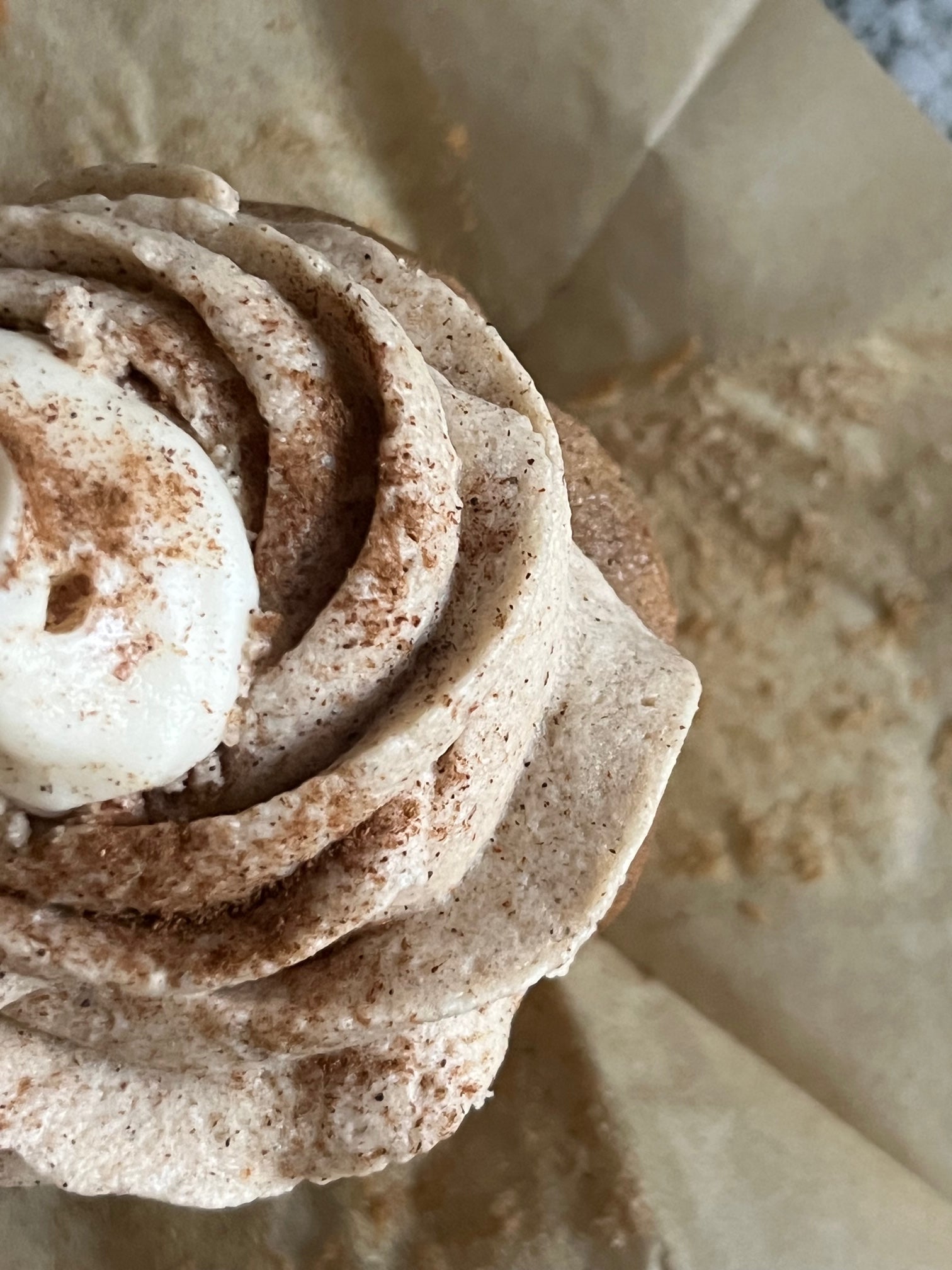 Overhead image of half a cupcake with gorgeous chai honey frosting sprinkled with cinnamon 