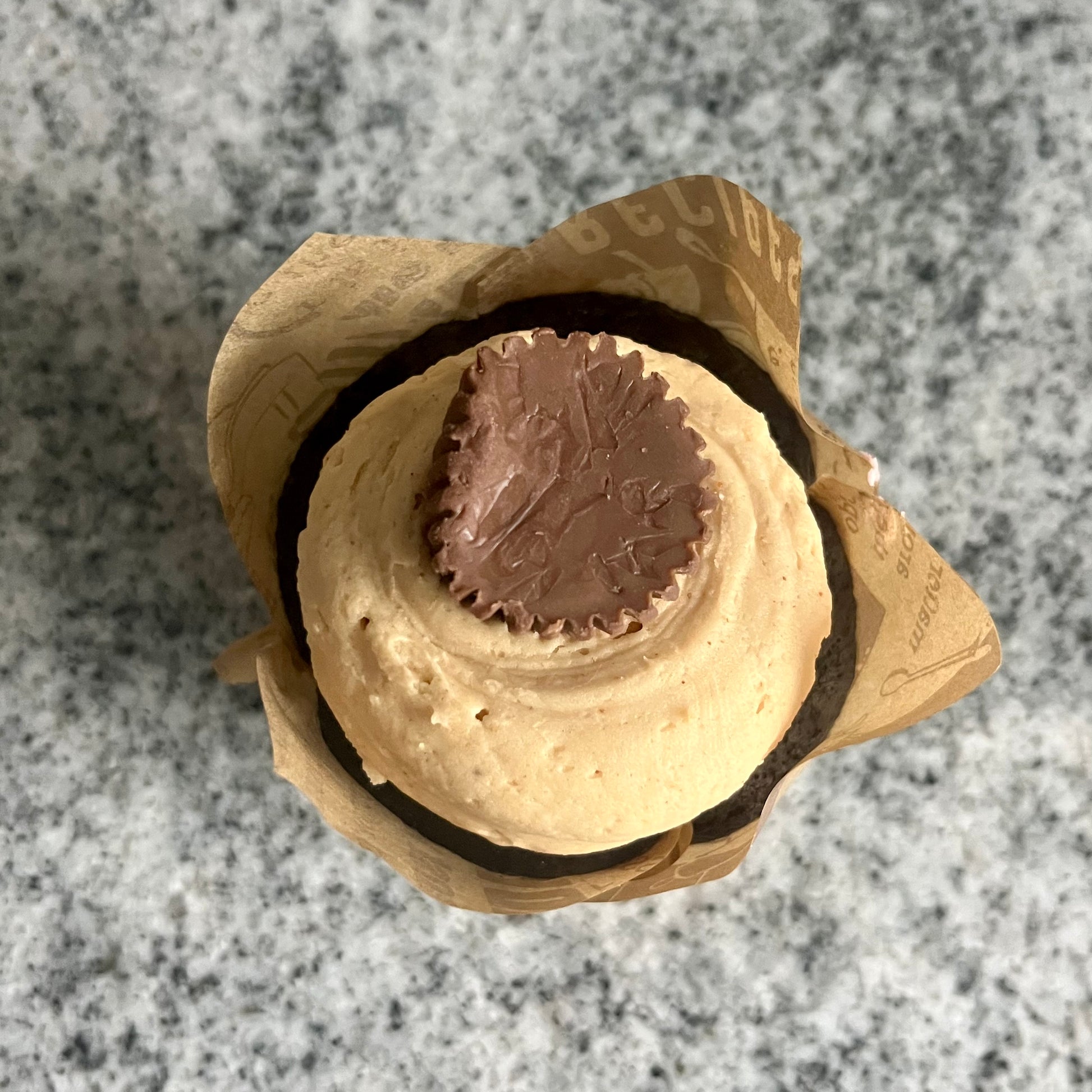 Top view of A decadent chocolate cupcake with a thick pile of peanut butter frosting and a peanut butter cup. 